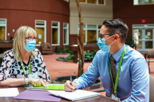 Two people sitting at a table conducting an interview | Leadership at Bethany Didsbury discussing designated supportive living